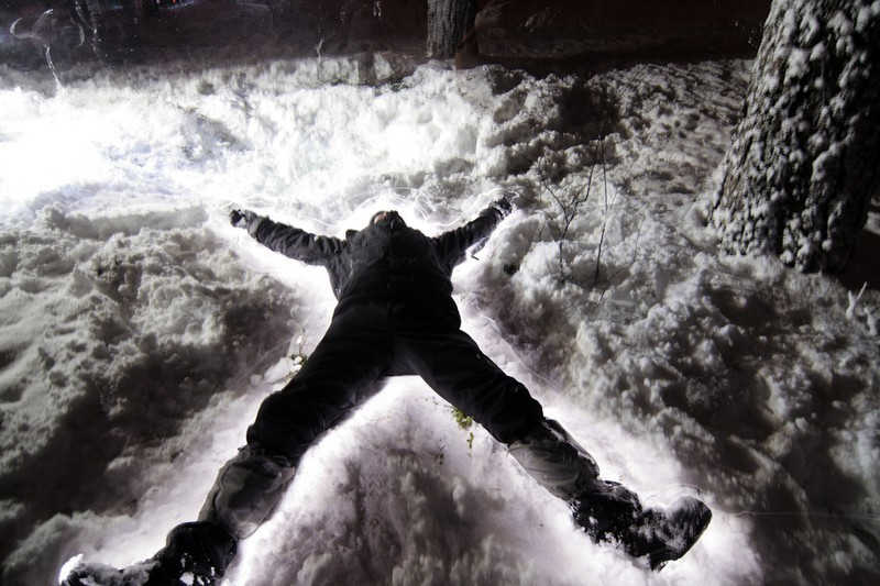 Podświetlona nocą leżąca postać na śniegu.