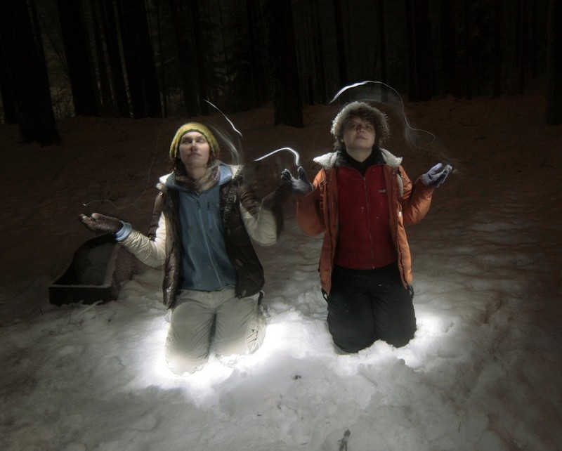 Podświetlone nocą dwie postacie w lesie zimą